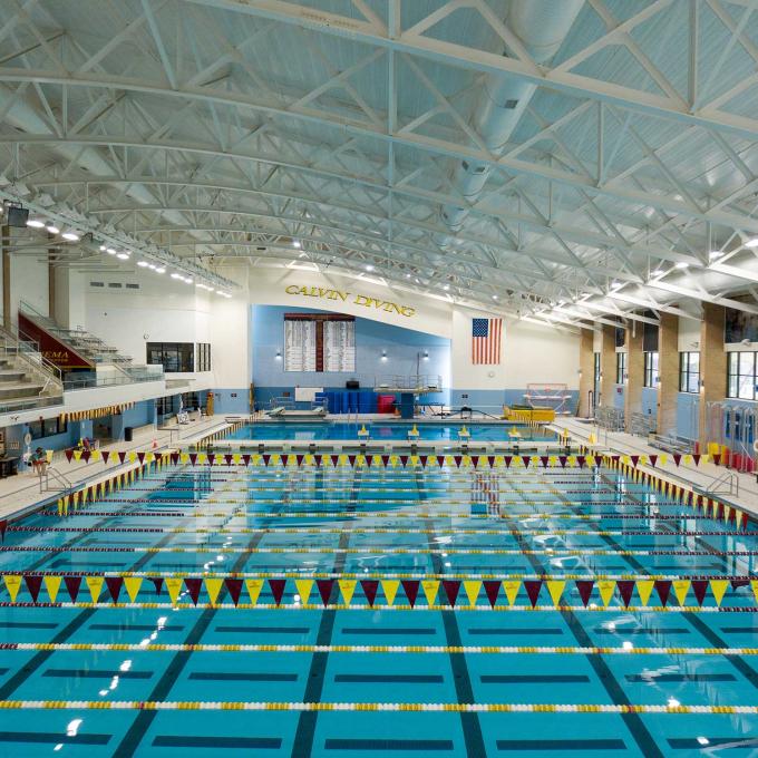Venema Aquatic Center, an olympic-sized pool with maroon and gold flags, bleachers, and a diving section.