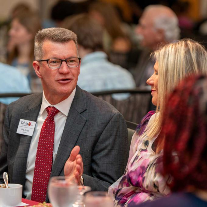 President Elzinga speaks with others at the table at a dinner event.