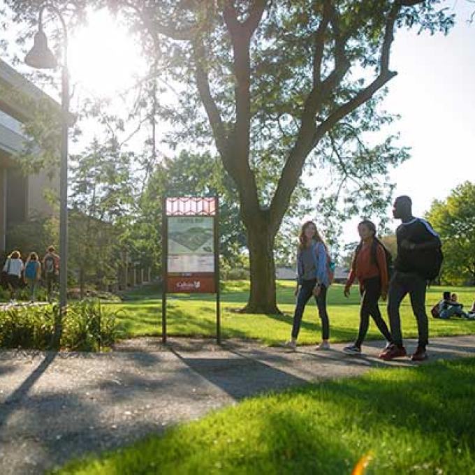 Calvin University students walking on campus with sunshine in the background