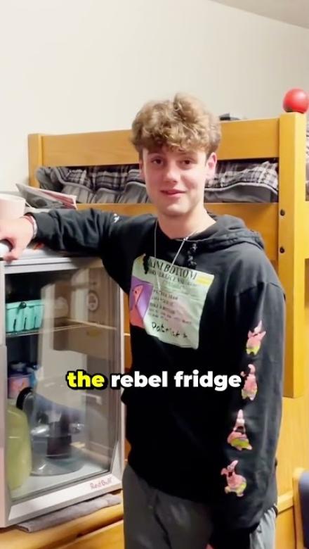A calvin student stands in front of his lofted bed.