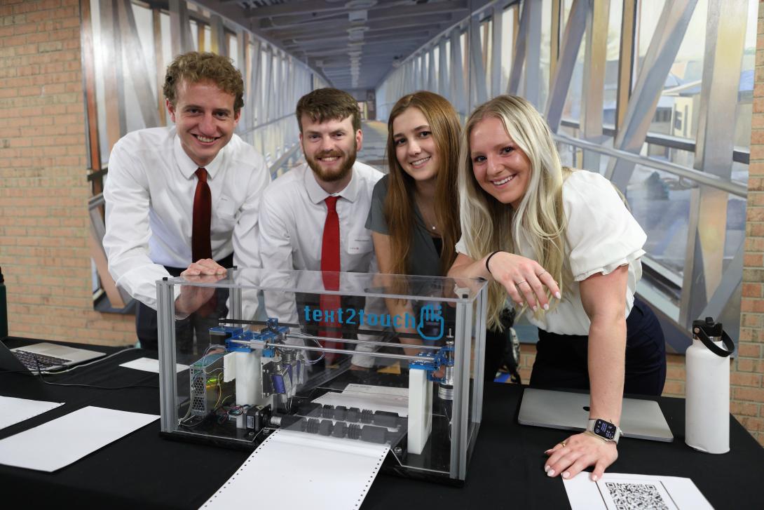 Engineering students smile with their senior design project.