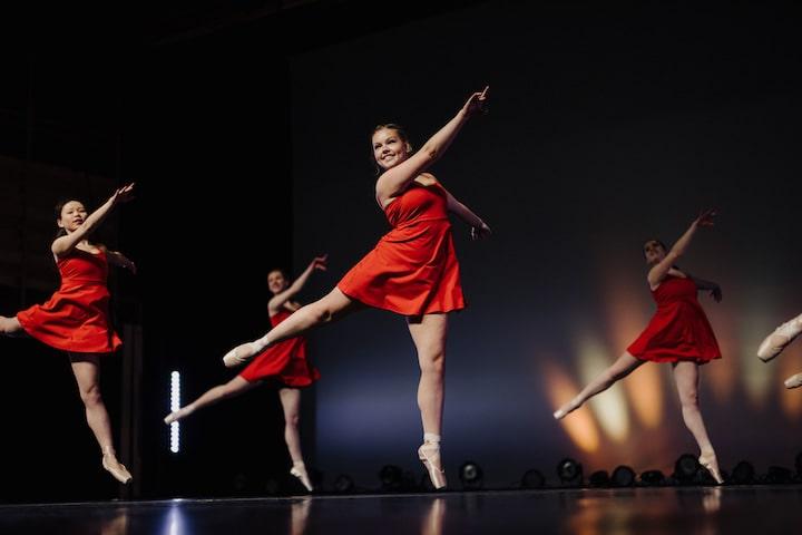 Pointe dancers in red leotards perform on the stage at Calvin University.