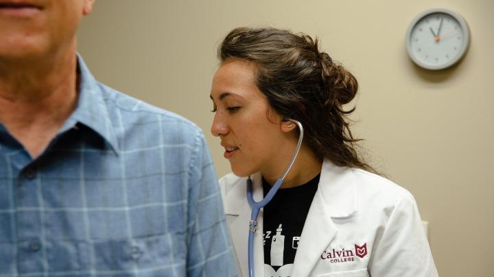 A pre-med student checks the heartbeat of a patient.