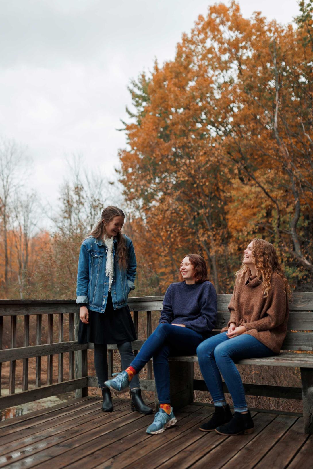Three students at the Calvin nature preserve on a cloudy fall day with yellow trees.