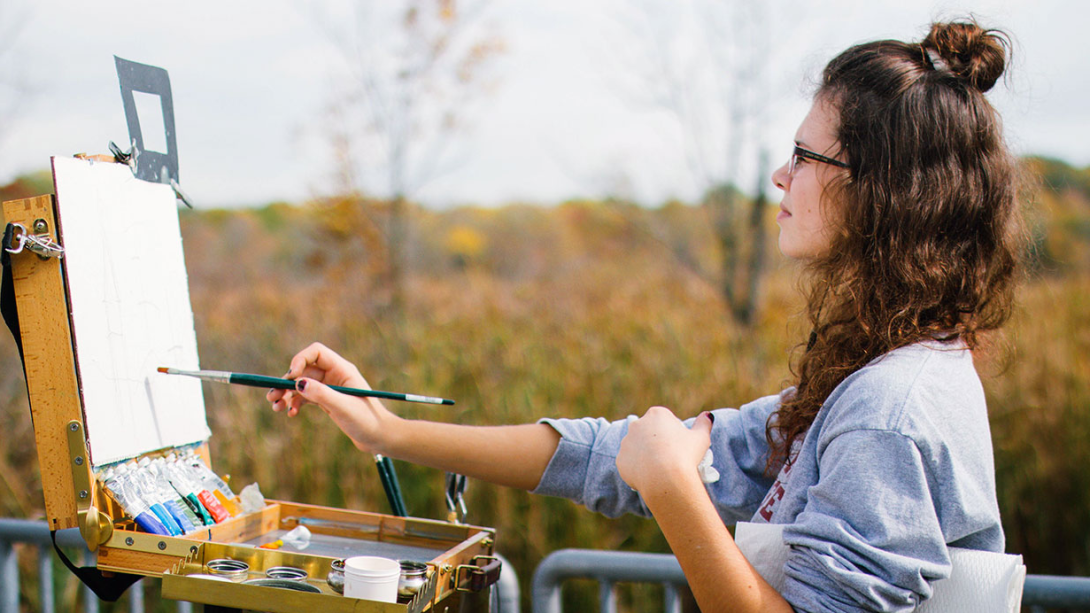 Woman painting near a field