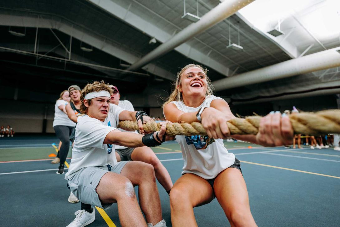 A group of male and female college students play tug of war at a residence life event at Calvin University.