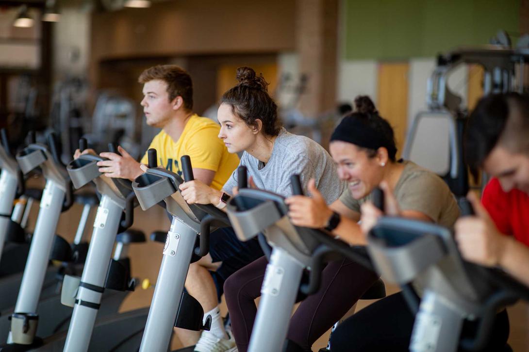 Four students on stationary bikes during a spin class.