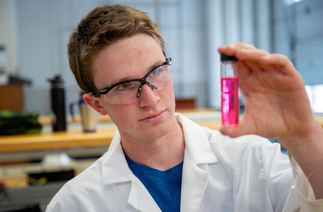 Student holding a vial of pink liquid