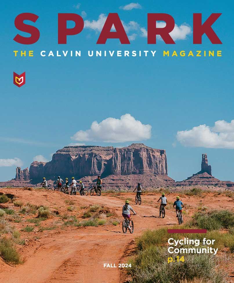 Cover of Spark magazine, with cyclists on mountain bikes, biking through Monument valley with red rock cliffs and blue sky in the distance.