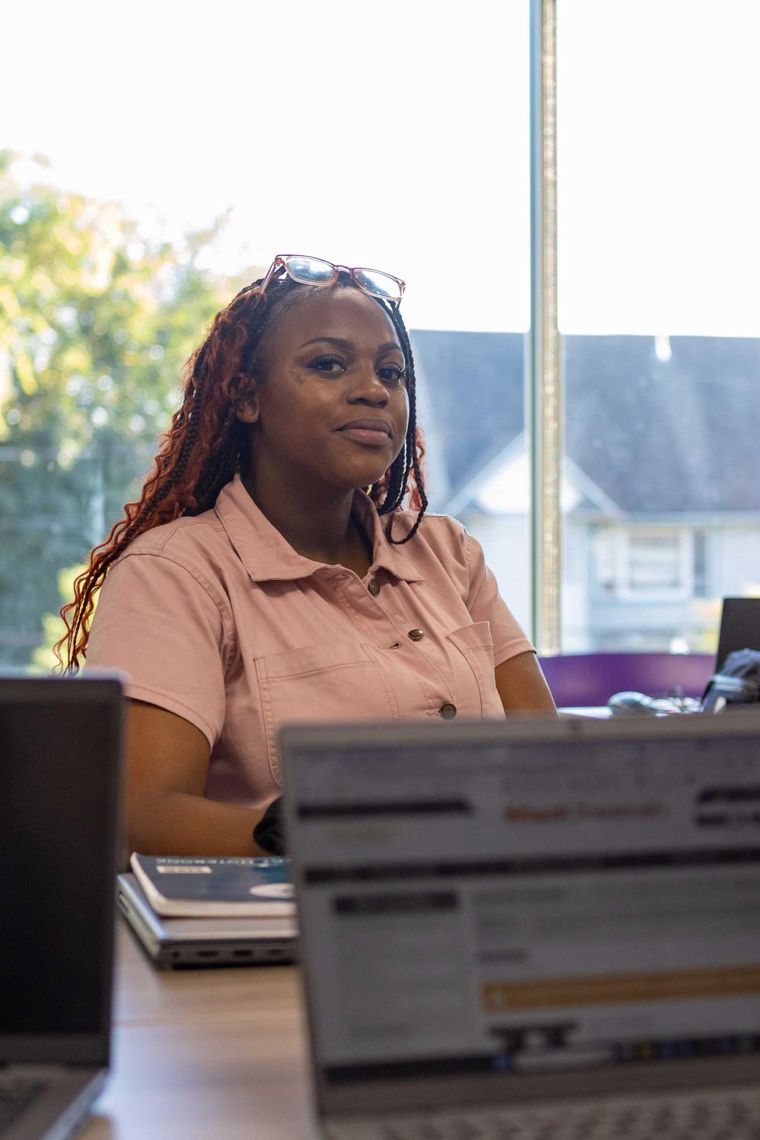 A Calvin University Wayfinder student sits at a table with notebooks and a laptop.