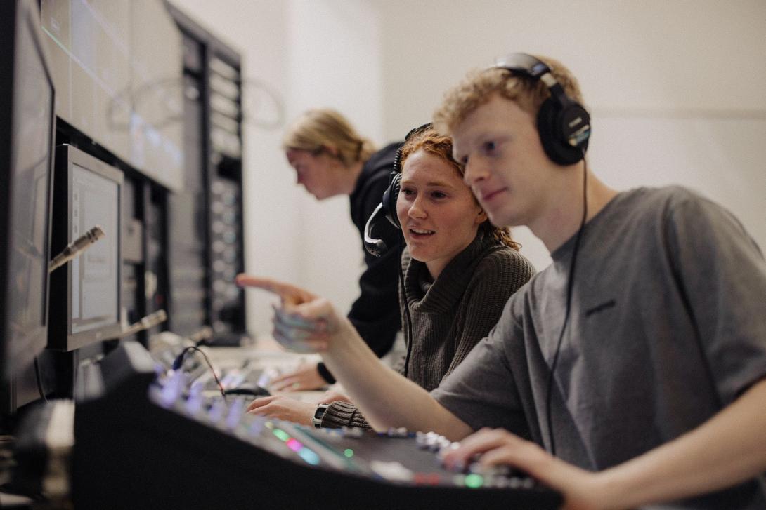 Three students at a media board