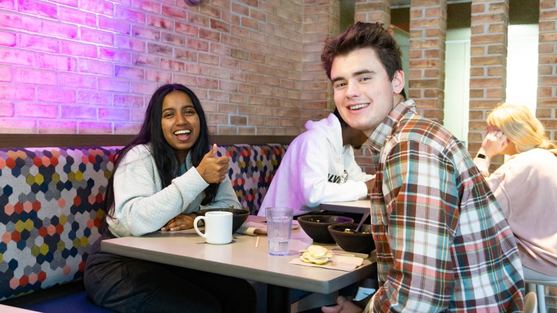 Two students dining at Commons face camera, posing with smiles.