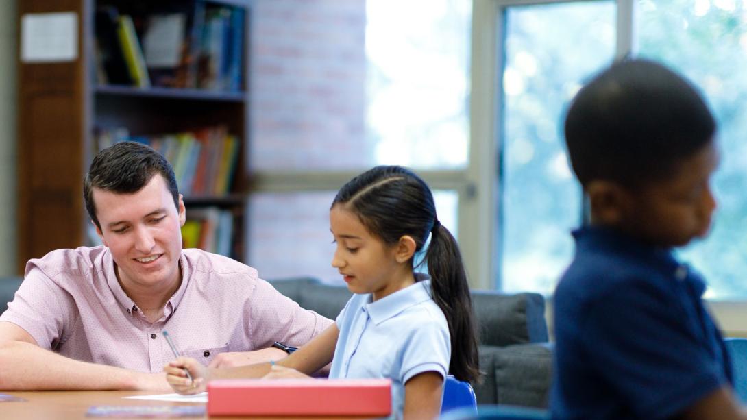 A young student and teacher at a table