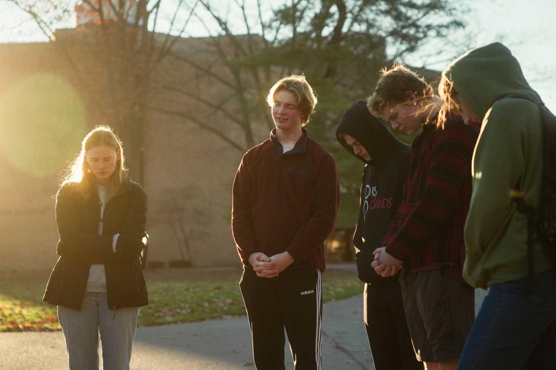 A group of students prays on the commons lawn at Calvin University.