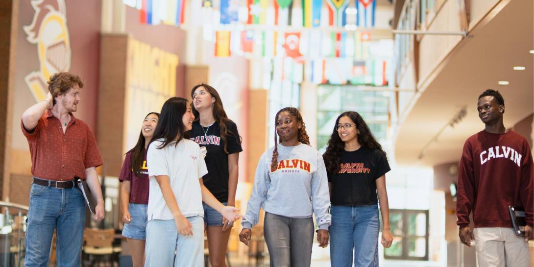 Students walk in the Spoelhof Fieldhouse Complex Lobby with international flags overhead