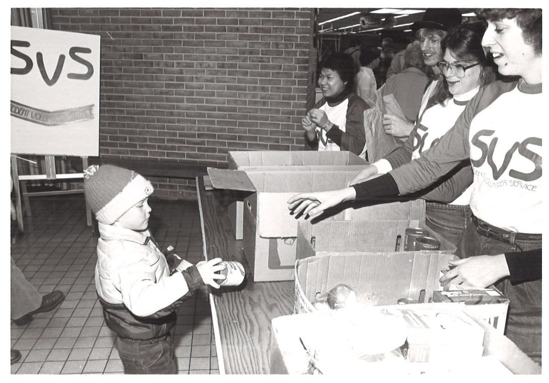 Child giving supplies to a Service-Learning food drive in old vintage photo