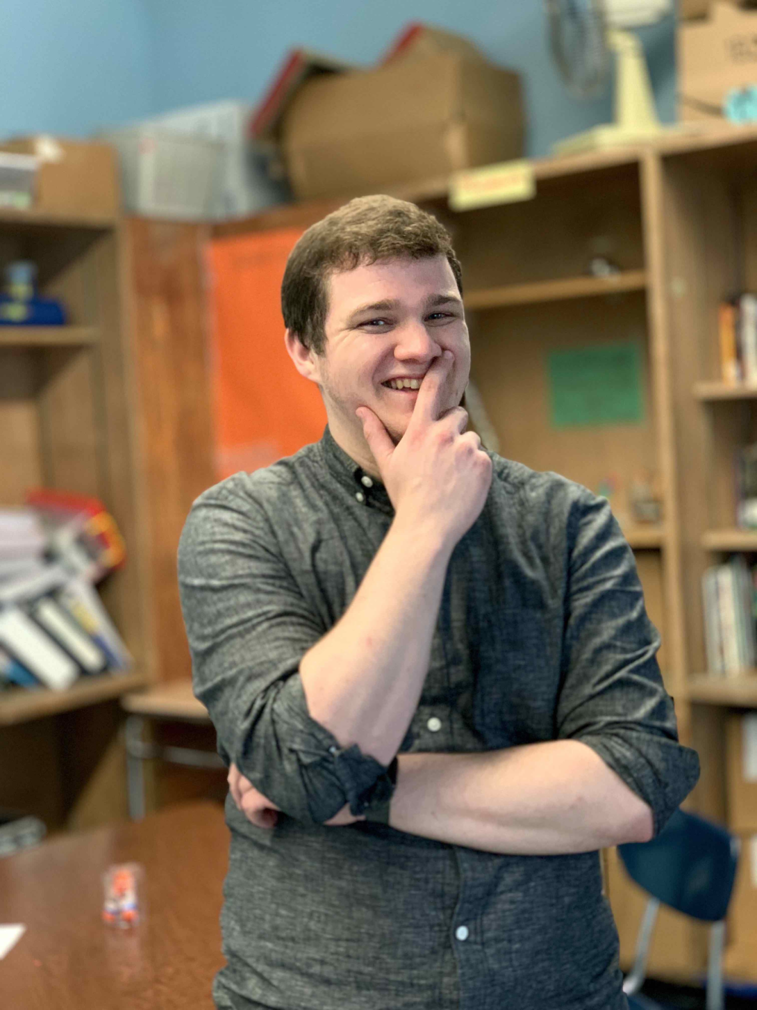 Nathan Stripp standing in his classroom in a gray button down shirt
