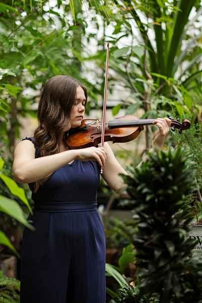 Violinist playing in greenhouse.