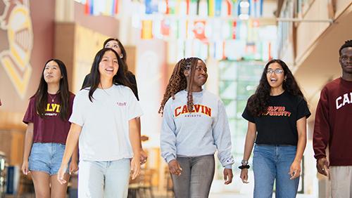 Calvin students walking in the Spoelhof Fieldhouse Complex under the international flags