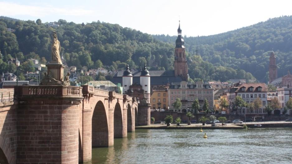 image of a brick bridge with arches over a river with mountains behind