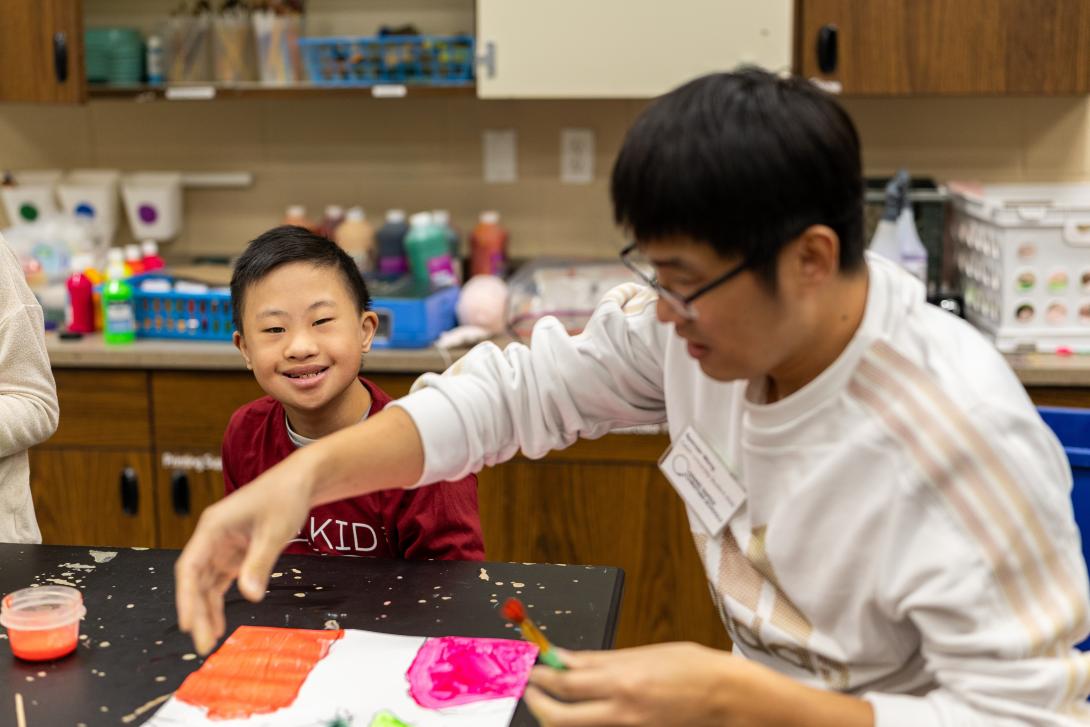 Calvin student intern working at a table with a young child.