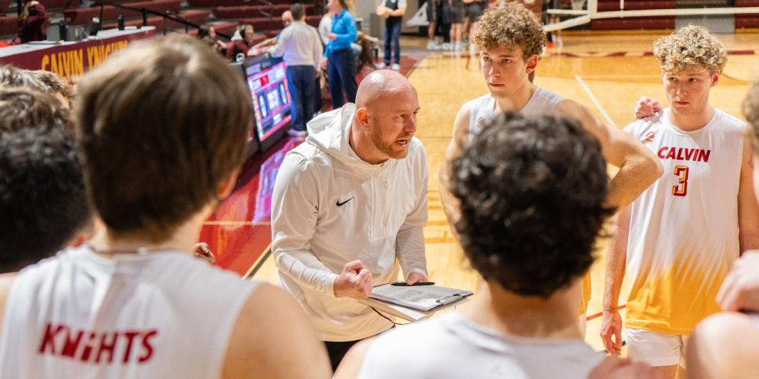 Coach Aaron Sagraves talks to his Calvin men's volleyball team in the huddle.