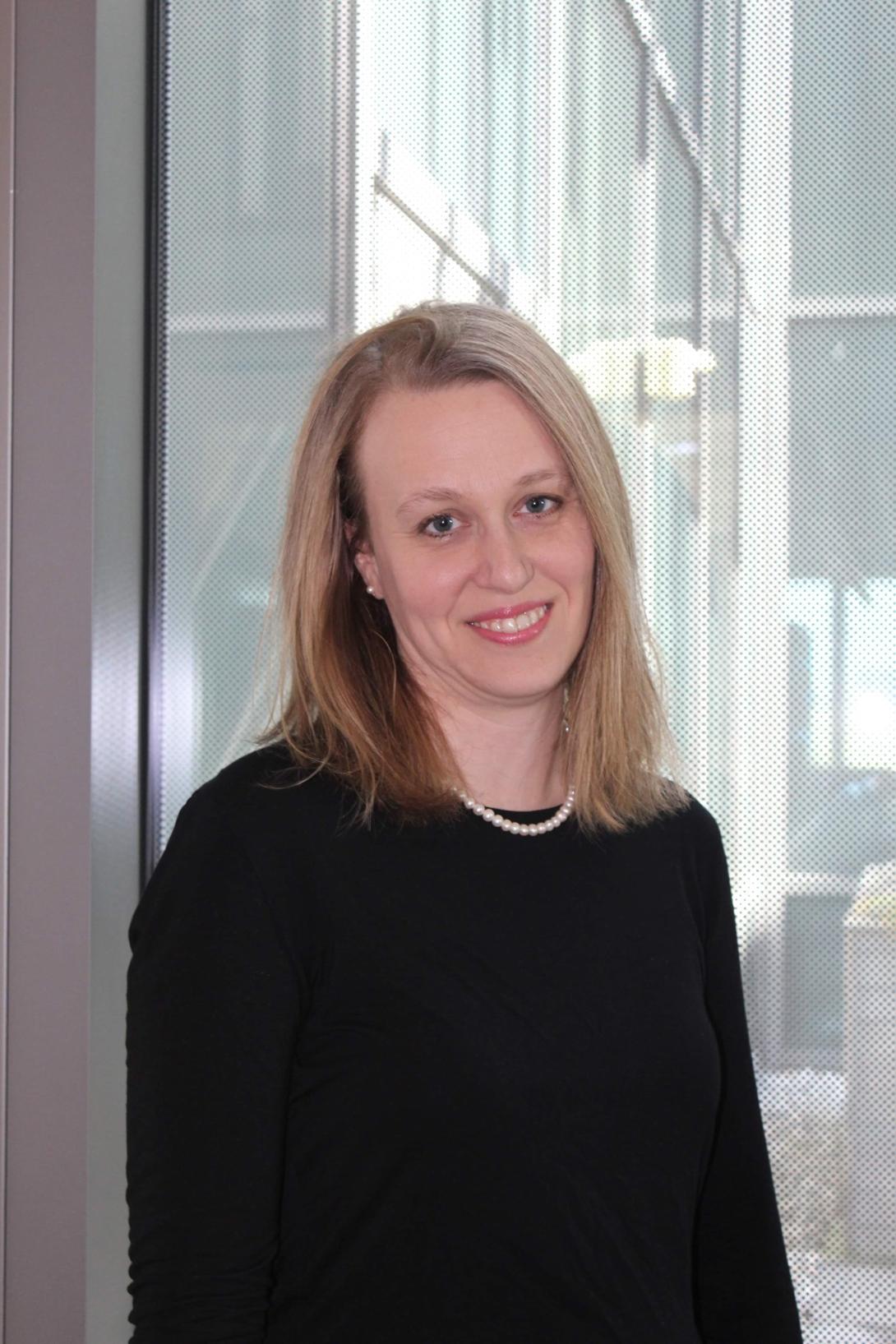 Headshot of Jenny Gill in a black shirt in front of a window