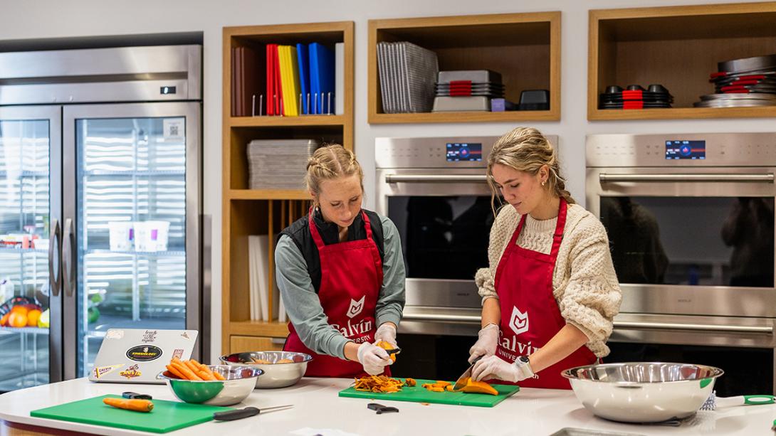 Two students chop carrots inside the Nutrition Lab at Calvin University.