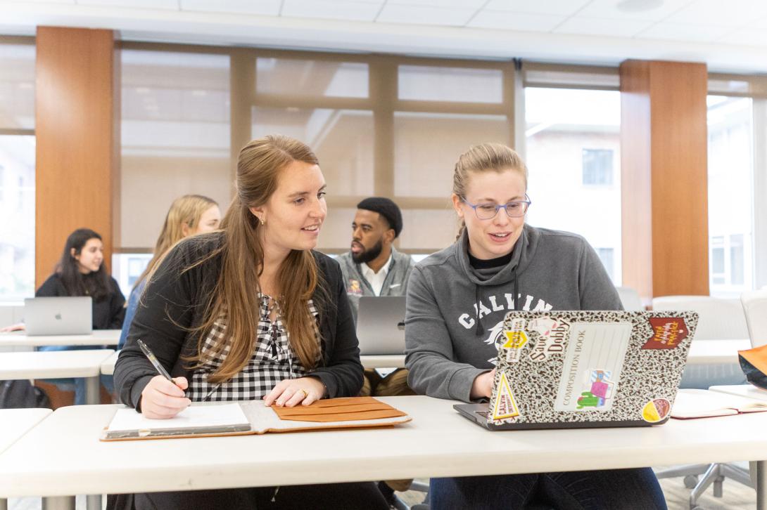 Calvin graduate students work on group projects at desks in a classroom.