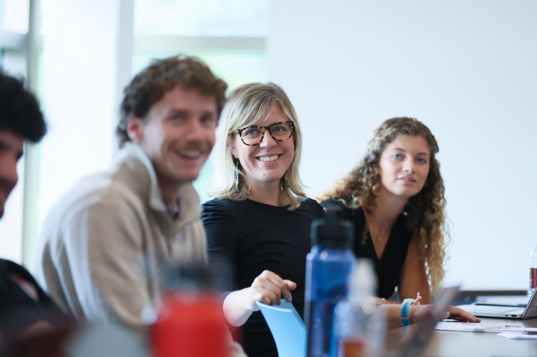 Three MBA graduate students sit at a desk and work on a group project.