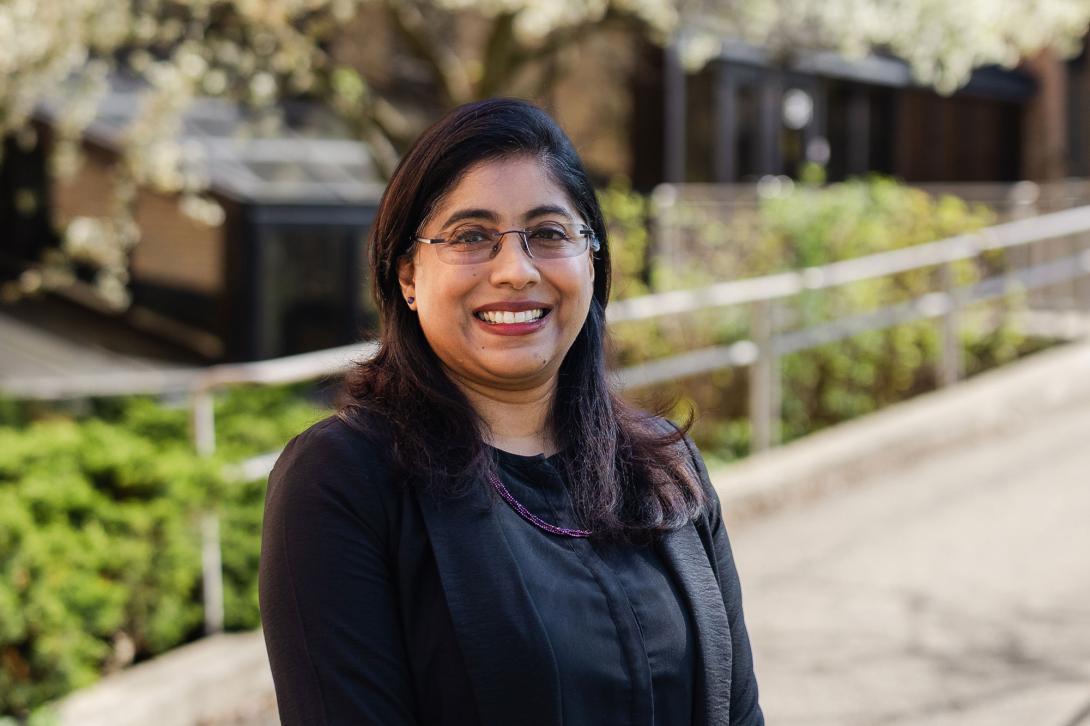 Professor Elizabeth Oommen poses in front of a walkway on Calvin's campus.