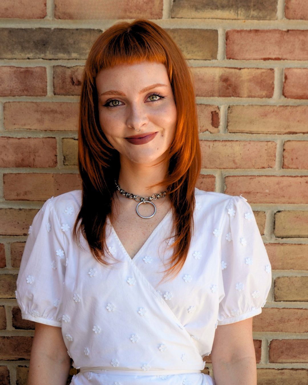Woman with red hair standing in front of brick wall. 