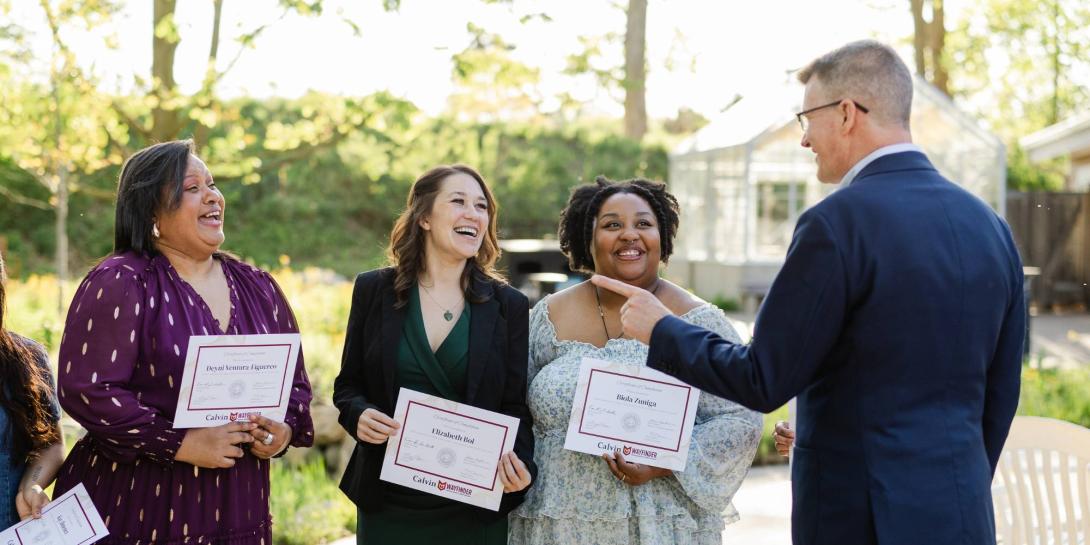 Elizabeth Bol '26 and fellow graduates from the Wayfinder Program talking with Calvin University President Greg Elzinga outside.