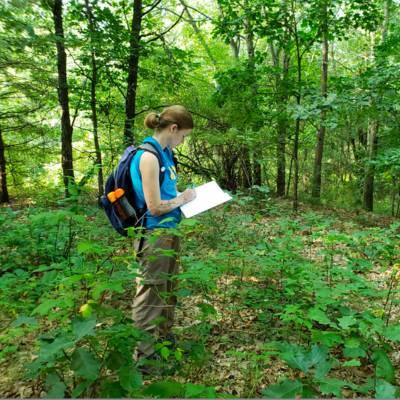 A student documents something in the woods