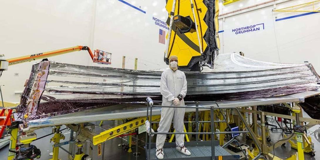 Adam Marquardt standing in the clean room in front of a telescope that's going to be launched into space.