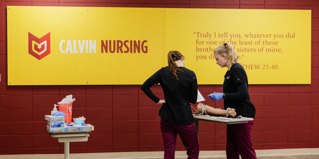 Two Calvin Nursing students practicing placing an IV in he classroom