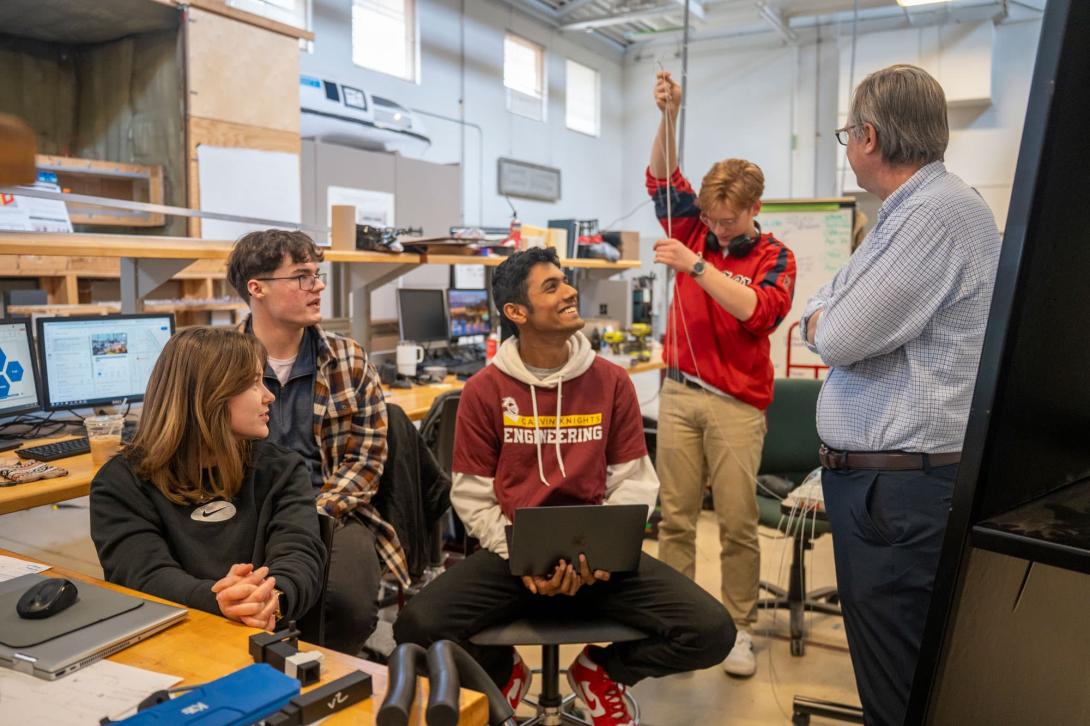 A group of five Calvin University Engineering students and a professor work together in the Engineering lab