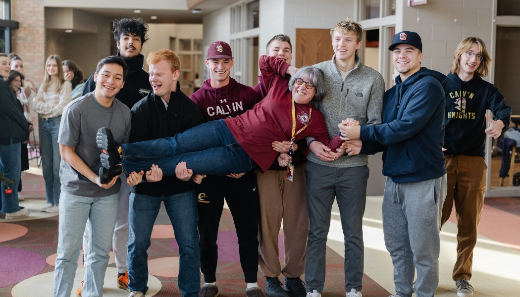 Professor Holberg being lifted up by a group of smiling students. 