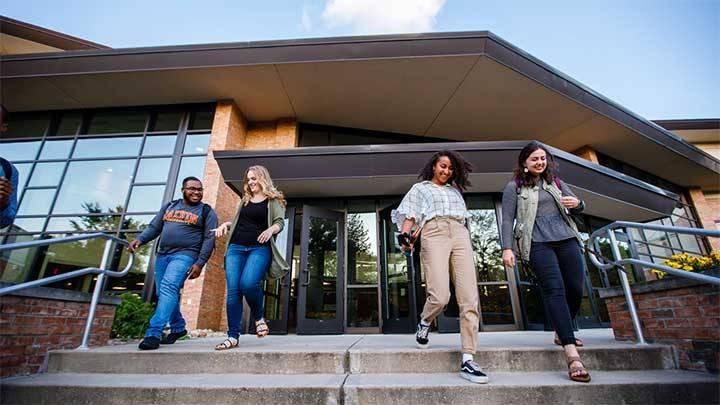 Four students walking down a staircase out the entrance to a university building