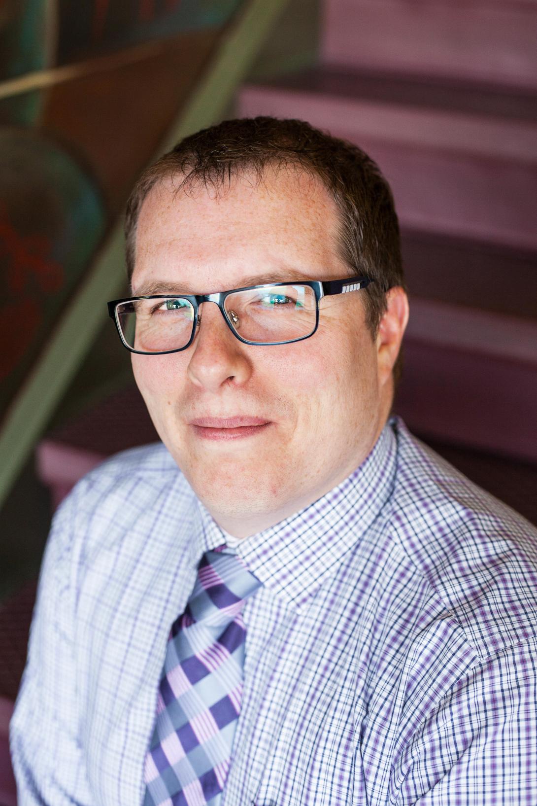 Robert Joustra headshot photo with red stairs in background