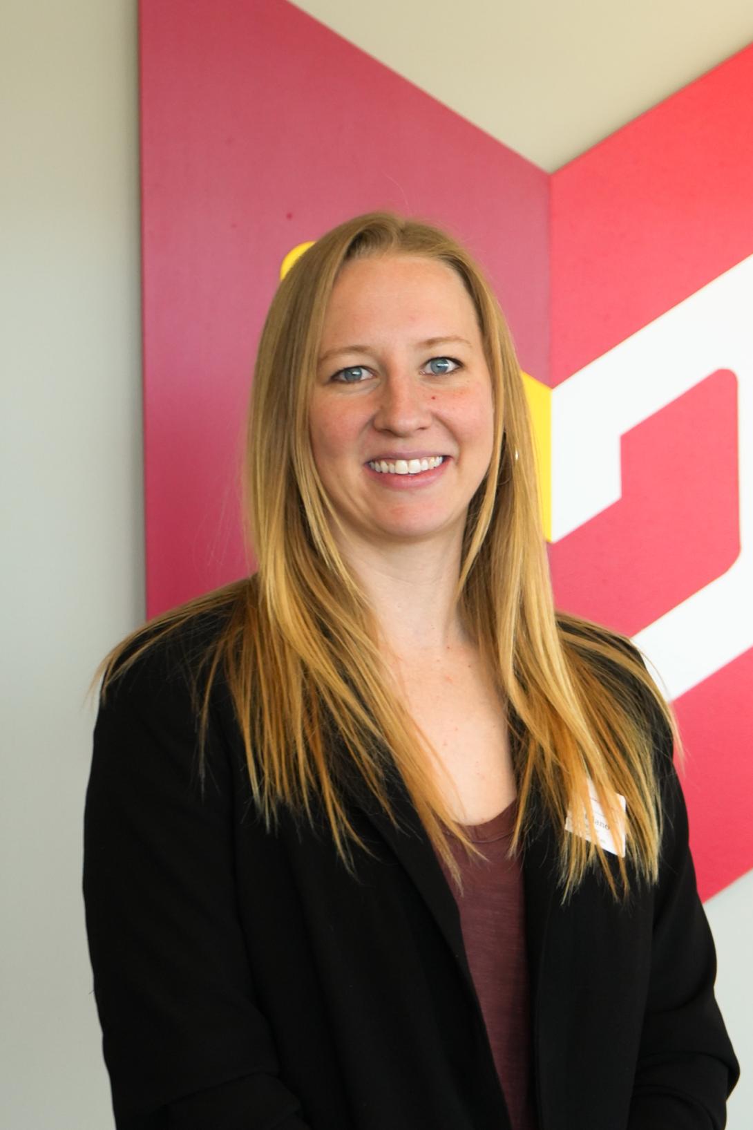 Woman in black tailored jacket with long blonde hair smiling in front of Calvin Wayfair symbol.