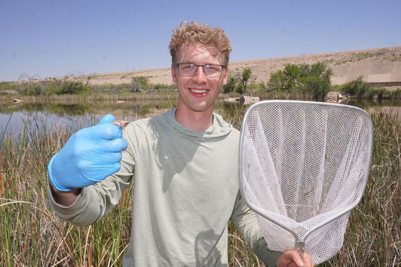 Braden DeWeerd with a net in a marshy area.