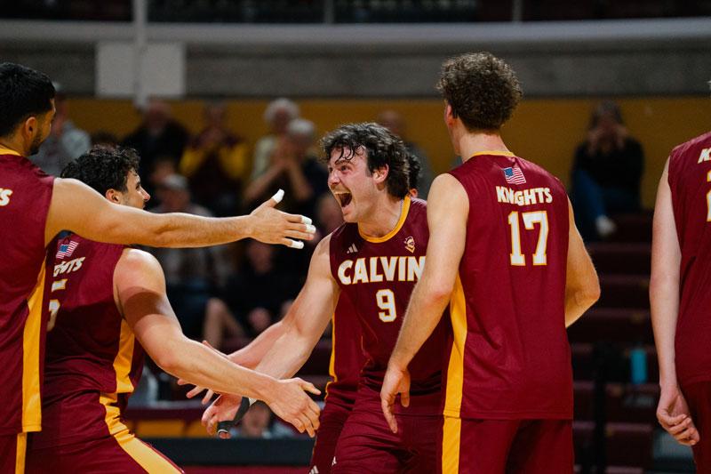 Calvin Men's volleyball teammates give high fives after winning a point. 