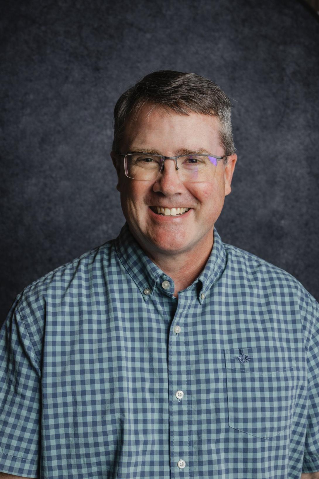 Fred Haan smiling headshot with blue background