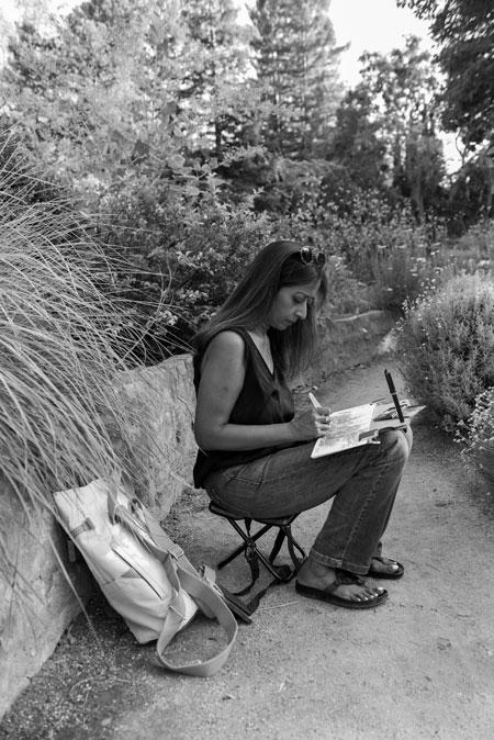 Priya Ramchandran sketches while sitting on a nature path.
