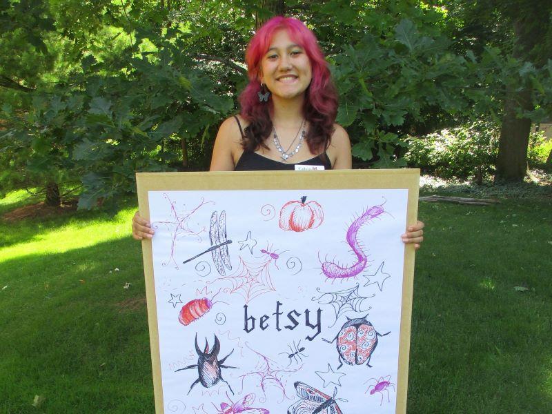 The FYRES coordinator standing holding a sign that says "Betsy"