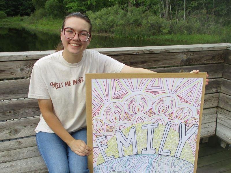 A FYRES mentor sitting and holding a sign that says: 