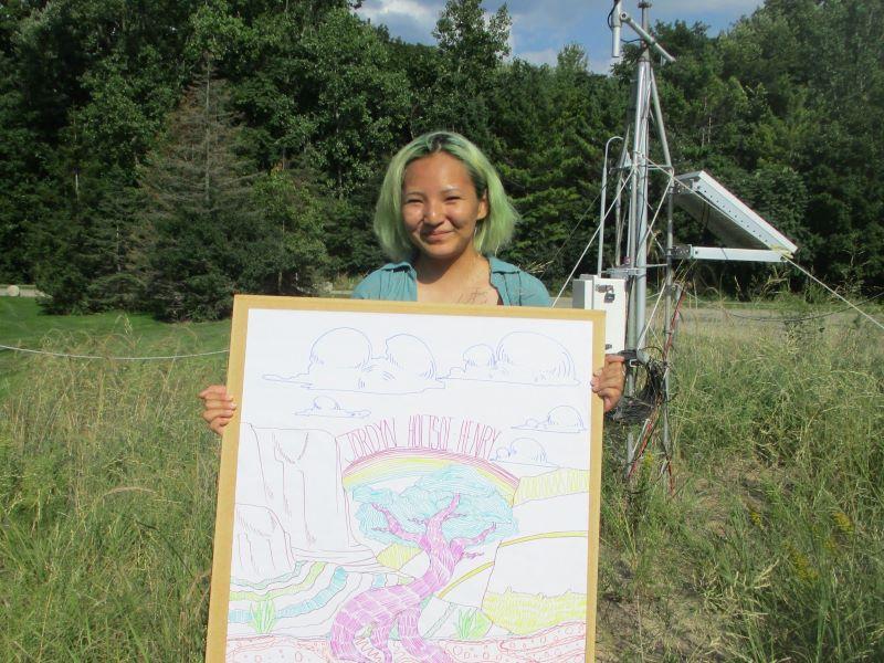 A FYRES mentor sitting and holding a sign that says: "Jordyn"