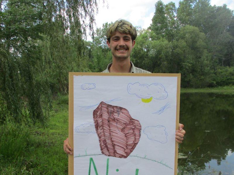 A FYRES mentor holding a sign that says: "Nick"