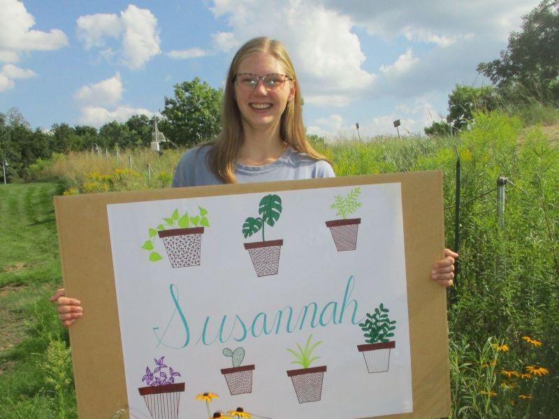 A FYRES mentor holding a sign that says "Susannah"